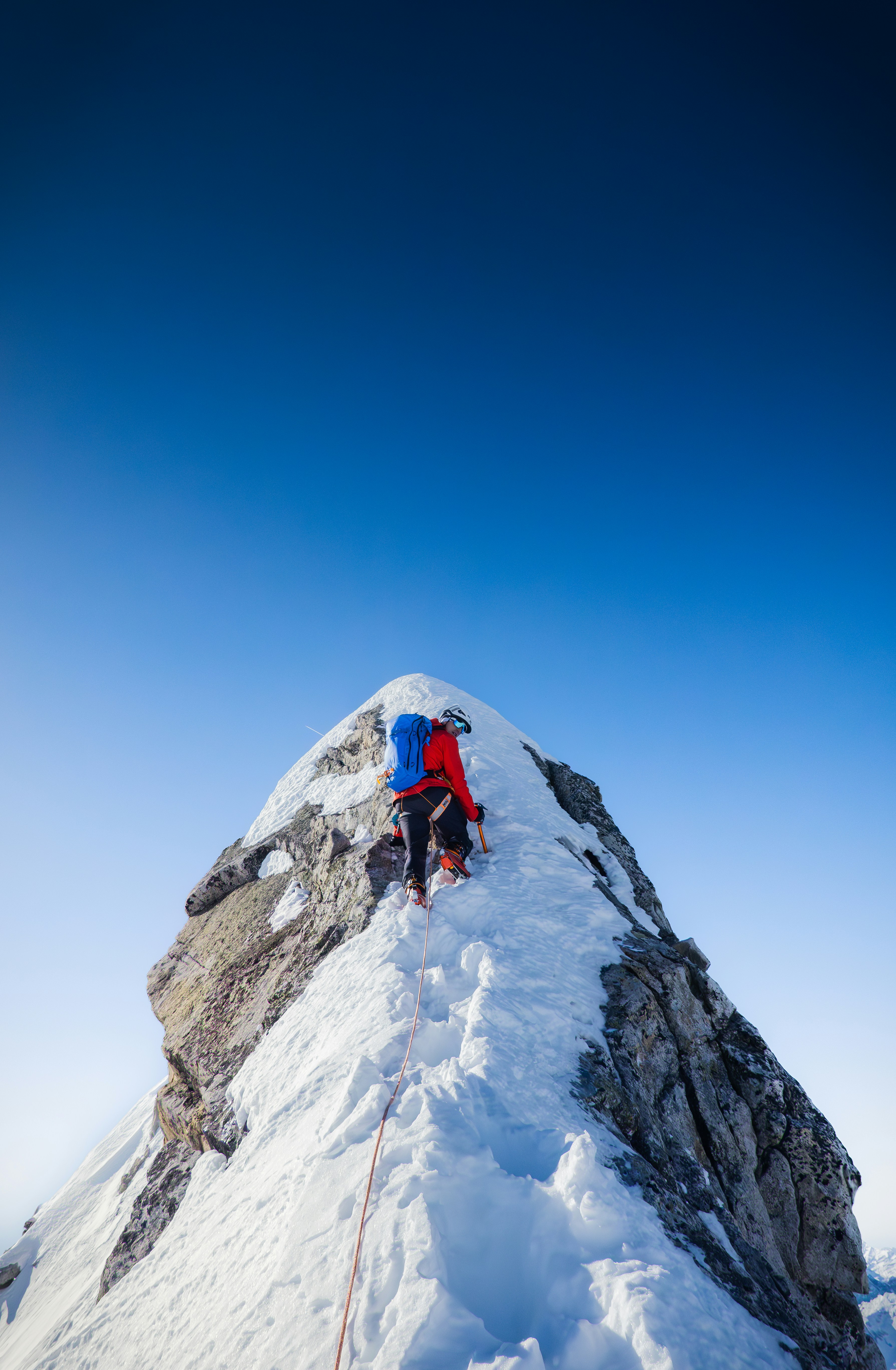 A climber ascending a snow-covered mountain ridge