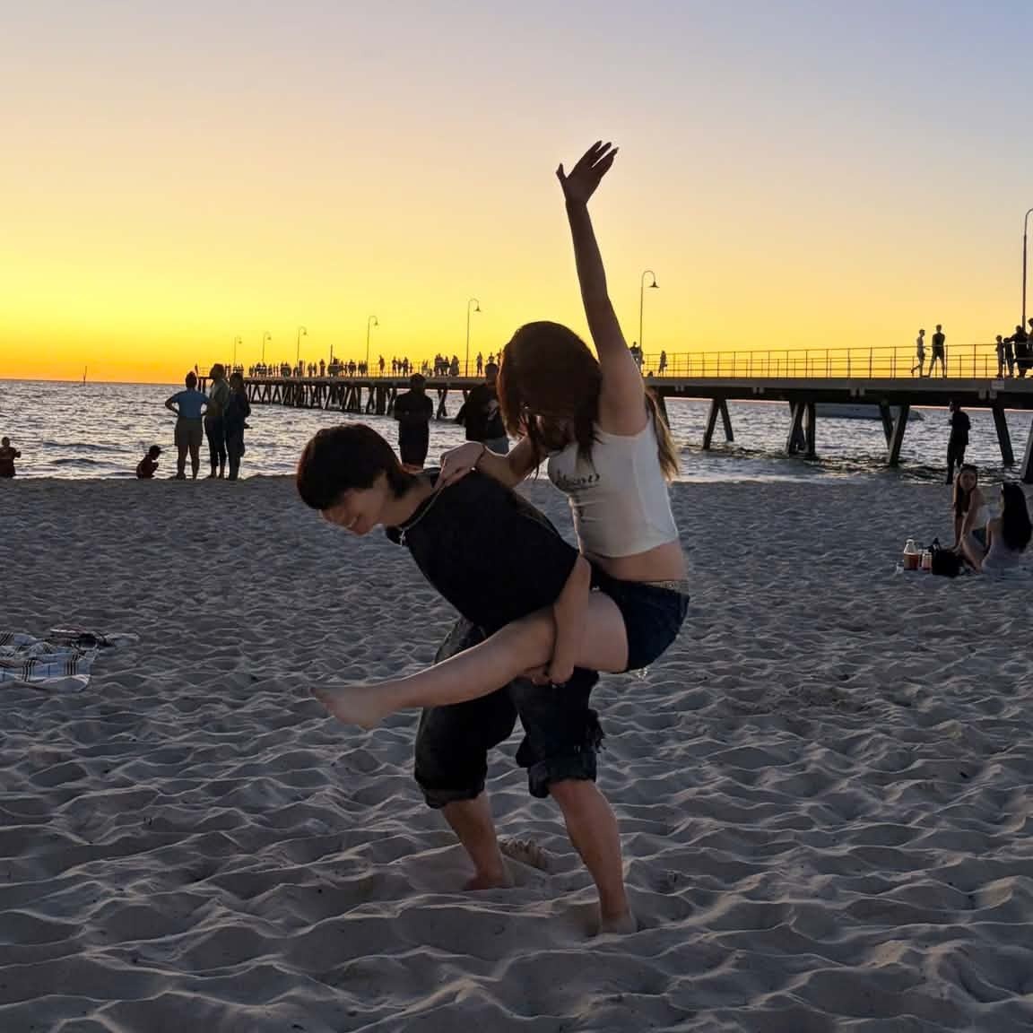 A couple playing together on a beach at sunset